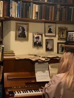 a woman sitting at a piano in front of a bookshelf filled with books