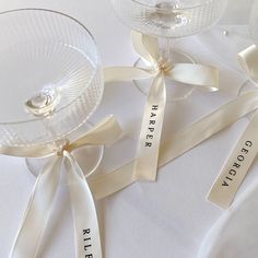 three wine glasses with ribbons tied around them on a white tablecloth, one is empty and the other two are empty