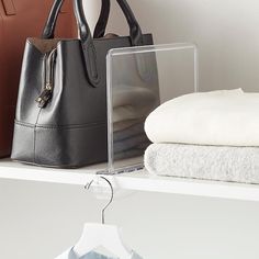 two purses are sitting on a shelf next to towels and folded clothes in front of them