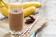 a glass filled with chocolate milk next to bananas