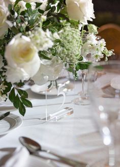 the table is set with white flowers and silverware