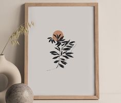 an art print with black and white leaves in front of a gray wall next to a vase