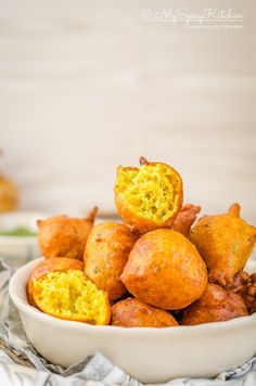 a white bowl filled with fried food on top of a cloth covered table next to silverware