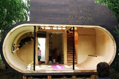 a person sitting on the ground in front of a wooden structure that looks like a boat