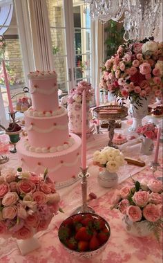 a pink cake sitting on top of a table covered in lots of flowers and candles