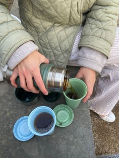 a person pouring something into some cups on the ground with their hands and legs extended