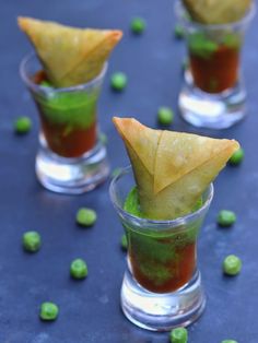 three small cups filled with food and garnished with green peas on the side