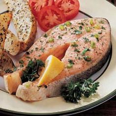 a white plate topped with fish, bread and tomatoes