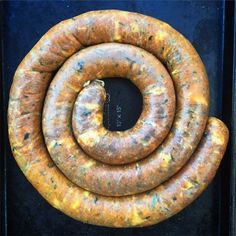 two large sausages sitting next to each other on top of a black surface with yellow and green flecks