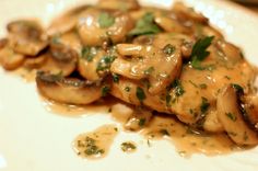 a white plate topped with mushrooms covered in gravy