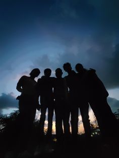 a group of people standing next to each other in front of a sky filled with clouds