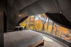 a bedroom with a large window overlooking the trees and hills in the fall season is shown