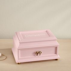 a pink jewelry box sitting on top of a table next to a pair of scissors