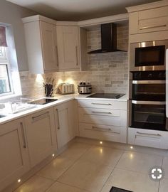 a kitchen with white cabinets and lights on the counter tops, along with a stove top oven