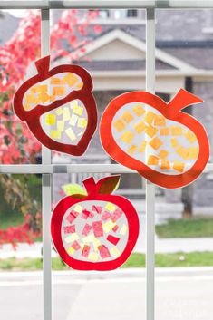 three cut out pieces of fruit sitting on top of a window sill in front of a house