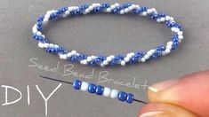 someone is making bead bracelets with blue and white beads on the end of a needle