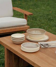 the table is set with plates, bowls and utensils for dinner on it