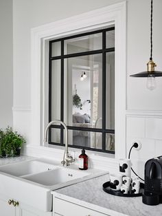 a kitchen with white cabinets and marble counter tops is pictured in this image, there are plants on the window sill