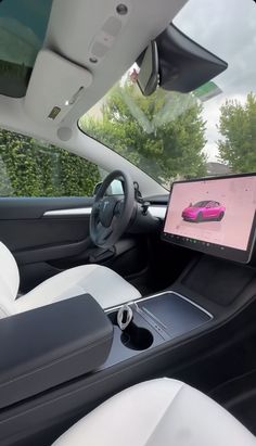 the interior of a car with a laptop on the dashboard and an image of a pink car