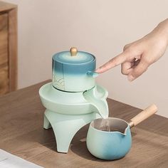 a person is pouring water into a cup with a wooden spoon in front of it