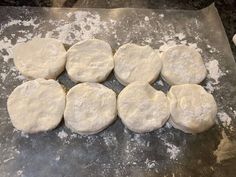 eight uncooked pizza doughs on a baking sheet