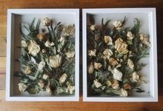 two white boxes filled with flowers sitting on top of a wooden floor next to each other