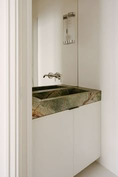 a bathroom sink sitting under a mirror next to a wall mounted faucet in a bathroom