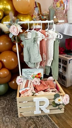 a wooden crate filled with baby clothes next to balloons and other items in the background