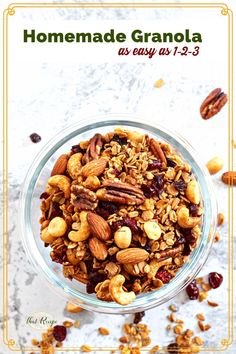 homemade granola in a glass bowl with nuts and cranberries on the side