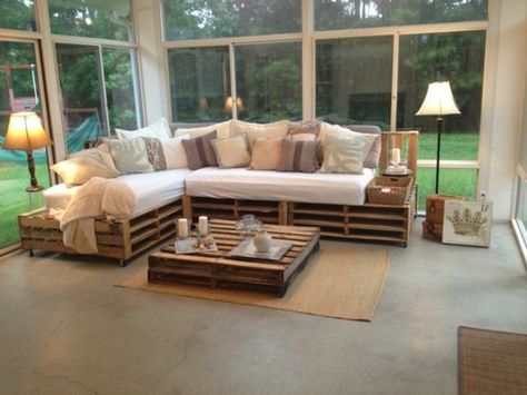 spacious-bright-living-room-with-large-windows-containing-a-pallet-couch-decorated-with-white-cream-and-beige-cushions-with-a-pallet-coffee-table-nearby Pallet Couch Cushions, Palette Sofa, Pallet Furniture Couch, Pallet Furniture Cushions, Table Palette, Diy Pallet Couch, Pallet Home Decor, Diy Pallet Sofa, Pallet Furniture Designs