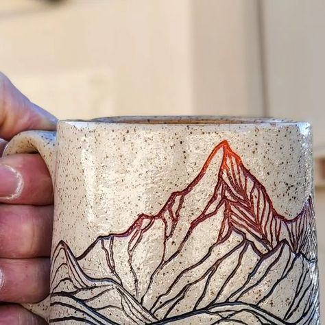 Ty Brookhart on Instagram: "Looking through the archives as I plan my year in the studio. These mountain mugs were a fan favorite. I really never tire of them either because carving them is like taking an imaginary backcountry trip - there's a lake behind that ridge fed by the snowmelt from that ragged peak, and with a little luck we'll be eating trout cooked on the coals from the fire.... Maybe it's a bit Bob Ross of me, but honestly, I watched him a lot on PBS as a kid; there were only 3 channels on our 13 inch TV. . . . . #mugshotmonday #mountainmade #coffee #coffeemug #sgraffito #modernmaker #waketomake #madeincolorado #art #design #designisinthedetails #americanartisan #designermaker #madeintheusa #claycarving #handmadecurator #design #designer #lovedesign #designlover #artanddes Mountain Carving Pottery, Carving Pottery Mugs, Sgraffito Mountains, Mountain Mug Pottery, Simple Sgraffito Designs, Sgraffito Mug, Mug Shapes Pottery, Pottery Mountains, Mountain Mugs