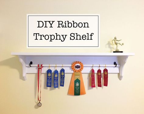 I did this project about two months ago when I was looking for a nice way to display our oldest’s growing collection of award ribbons and medals but couldn’t find a display setup that I liked or was remotely affordable. The whole project was super easy and done start-to-finish within two days. | This post contains affiliate links | Materials      lumber (I used a 1x8" board for the shelf top and 1x6" board for the back)  two decorative shelf brackets (or two pieces of wood cut at 45 de… Trophy And Ribbon Display Ideas, Diy Trophy, Woodshop Projects, Trophy Shelf, England Lifestyle, Decorative Shelf Brackets, Ribbon Display, Trophy Display, Award Ribbons