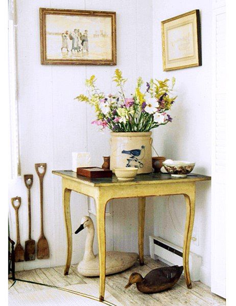 At Mellon’s house in Massachusetts, country-style flowers, including goldenrod and cosmos, fill a stoneware vessel atop a painted table; positioned beneath the table are bird sculptures that reference the wildlife in the area. Bunny Mellon, Bird Sculptures, Hand Printed Linen, Garden Designer, Cape Cod House, Country Houses, Bird Sculpture, Painted Table, English Style