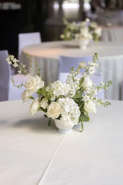 Floral compote arrangement made with all white flowers and placed on the guest tables Small Flower Wedding Centerpieces, All White Wedding Flowers Centerpieces, White And Cream Centerpieces, Small White Arrangement, Small White Floral Centerpieces Wedding, Elegant White Floral Arrangements, Long Table White Flowers, Small Compote Floral Arrangement, White Florals Wedding Centerpieces