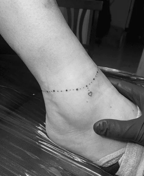 55 Anklet Tattoo Designs To Make Your Ankles Shine! Ankle Bracelets Tattoos For Women, Charm Anklet Tattoo, Anklet Tattoos For Women, Anklet Tattoo, Wrist Bracelet Tattoo, Ankle Tat, Tiny Tattoos For Women, Chain Tattoo, Tiny Wrist Tattoos