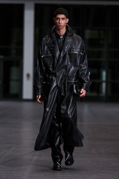 Photo from Vogue depicting a full length overszied leather trench coat with large zippered pockets. Underneath are baggy leather pants and black leather boots with silver zipper detailing Leather Jacket Outfit Men, Black Dress Coat, Trench Coat Outfit, Moda Paris, Trench Coat Men, Leather Trench, Mens Fashion Week, Menswear Fashion Show, Leather Trench Coat