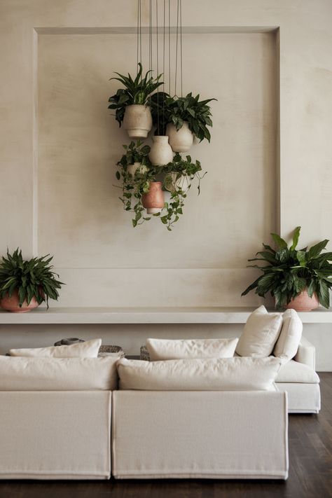 A vertical arrangement of hanging planters adding depth and greenery to the room. Hanging Shelf Plants, Plant Wall With Mirror, Plants Hanging From Ceiling, Hanging Plant Ideas, Plant Ledge, Wall Plants, Tiered Planter, Entry Wall, Hanging Plant Wall