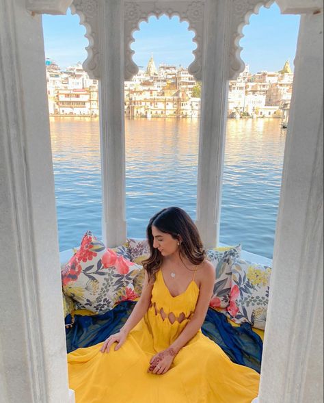 Girl wearing yellow maxi sitting under intricate stone detailed arch way with lake pichola in the background in udaipur Udaipur Photography Lakes, India Outfits Travel Summer, Outfits For Udaipur Trip Women, Photoshoot In Udaipur, Rajasthan Travel Outfit Ideas, Lake Pichola Udaipur Photography, India Photoshoot Ideas, Udaipur Picture Ideas, Rajasthan Photo Ideas