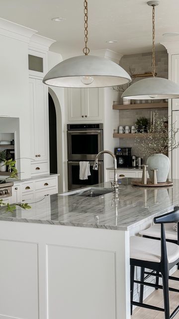 Megan West on Instagram: "I can’t believe our new kitchen was finished one year ago! We are obsessed with how it all came together from a style and function standpoint! This is definitely the area of the home we invested most heavily in! We love to cook and host and this is always our gathering place!  Paint color: BM White Dove Hardware: Top Knobs Pendants: Visual Comfort Countertops: Sea Pearl Quartzite  #homeremodel #remodeling #beforeandafterhomeedition #whitekitchencabinets #neutralhome #interiordesign #interiorinspiration #homeinspo" Elliot Pendant, Paneled Fridge, Bm White Dove, Sea Pearl Quartzite, Decorators White, Megan West, White Oak Cabinets, Lakefront Living, Appliance Pulls