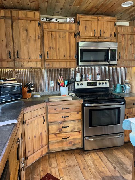 Rustic meets industrial in this kitchen. Pictured: Galvalume ceiling tiles. Farmhouse Kitchen Rustic Cabinets, Rustic Kitchen Cupboard Doors, Galvalume Ceiling, Rustic Kitchen Cabinet Doors, Barn Tin Kitchen Island, Burnt Wood Cabinets, Rustic House Remodel, Corrugated Metal Wall Kitchen, Rustic Kitchen Cupboards