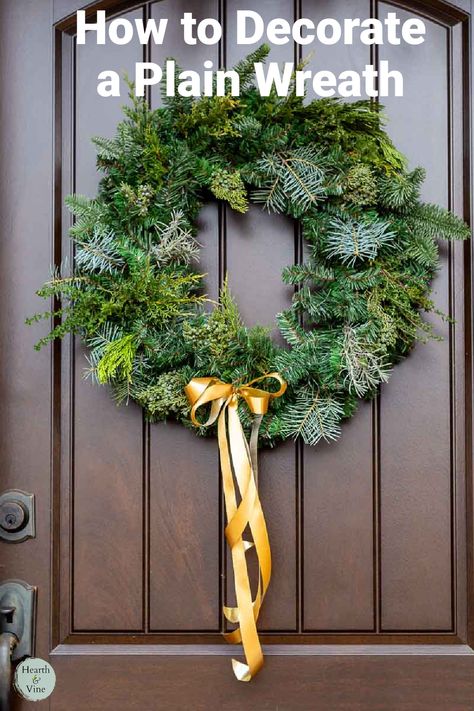 Faux evergreen wreath with added fresh greenery and a gold bow on a front door. Making A Fresh Pine Wreath, Christmas Wreaths Real Greenery, Grinch Wreath Natural, Farmhouse Evergreen Wreath, Christmas Wreath Supplies, Farmhouse Evergreen Christmad Wreath, Plain Wreaths, Artificial Christmas Wreaths, Christmas Decorations Wreaths