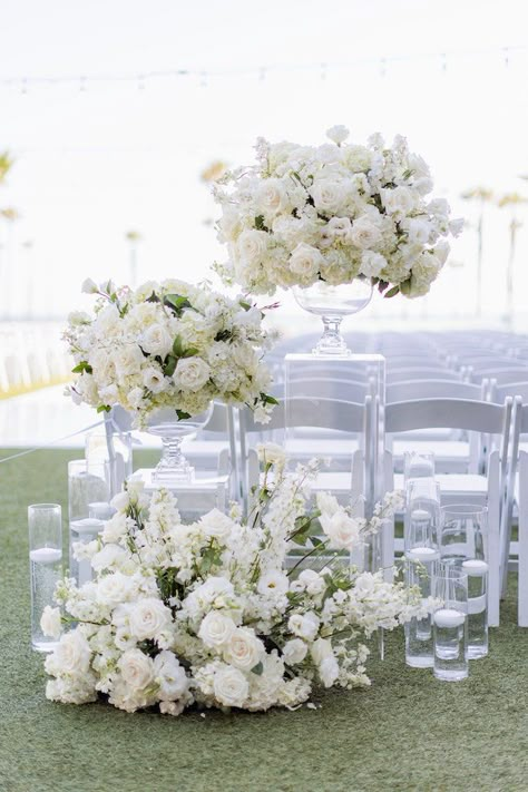 Wedding Flowers Floor Arrangements, Overhanging Flowers Wedding, Pedestal Flowers Wedding Ceremony, Ivory Wedding Florals, White Folding Chairs Wedding Ceremony, Floor Florals Wedding Ceremony, Wedding Decor White Flowers, White Wedding Centerpieces Elegant, Runway Style Wedding Ceremony