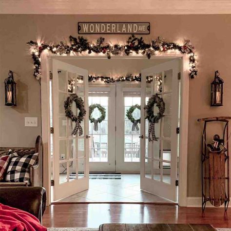 Enter into a winter wonderland through these white French doors decorated with Christmas wreaths. The wreaths are paired with black gingham bows. Black and glass candle sconces flank the double doors...   Image: my.farmhouse.fanatic.life Doorframe Decor Christmas, Christmas French Doors, Sliding Door Christmas Decorations, Christmas French Doors Decorations, Christmas Decor Sliding Glass Door, French Doors Decor Ideas, Christmas Patio Door, French Doors Christmas Decor, French Door Christmas Decor