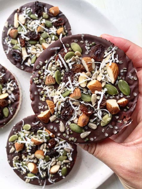 Picture of chocolate-coated rice cake topped with nuts and seeds. Rice Cake Toppings Sweet, Dark Chocolate Rice Cakes, Rice Cakes Toppings Sweet, Rice Cake Recipes Sweet, Vegan Rice Cake Toppings, Chocolate Rice Cake Ideas, Protein Rice Cakes, Chocolate Rice Cakes Toppings, Rice Cakes Toppings Healthy