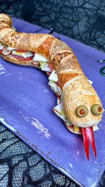 Genevieve LaMonaca on Instagram: "Slithering Snake Sub 🐍🥖 Follow @chefgenevieve for 50 Halloween inspired recipes #halloweenfood #HalloweenFoodIdeas #halloweeninspo #SlitheringSnakeSub #SpookySeason

Snake Bread Loaf:
1 can Pillsbury French bread dough
1 egg + 1 tsp water (eggwash)
Toppings: paprika, cracked black pepper, red pepper flakes, oregano and dehydrated onions

Directions: Stretch out dough to about 14 inches over a parchment lined sheet pan. Taper out the tail and form the head. Shape the dough to resemble a slithering snake.

Brush with egg wash then make your serpent markings. I used parchment paper to help guide me then sprinkled on paprika, cracked black pepper, red pepper flakes, oregano and dehydrated onions.

Make slits on the top then bake in 350° oven for 25 minutes t Pillsbury French Bread, Snake Sandwich, Slithering Snake, Snake Party, Dehydrated Onions, Sub Sandwiches, Bread Loaf, Halloween Inspo, Halloween Food