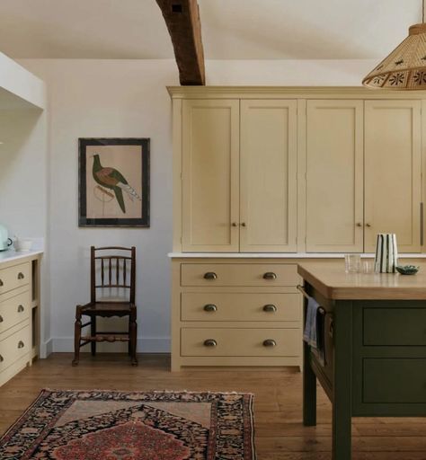 Kitchen with navy blue island in front on wooden floor with floor to ceiling cupboards on the back wall in buttery yellow with brass handles. To the right is a vintage wooden chair with old art work above. Wooden Island Kitchen, Warm Kitchen Ideas, Old Art Work, Vintage Wooden Chair, Cottage Core Home, Colonial Kitchen, Yellow Room, Kitchen Storage Solutions, Floor To Ceiling