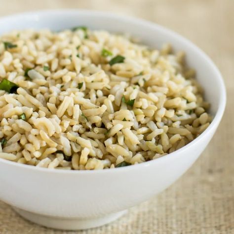 White bowl of Chiptole's Cilantro Lime Rice, pictured against a light brown background. Chipotle Brown Rice, Chipotle Cilantro Lime Rice, Rice In Rice Cooker, Chipotle Rice, Cilantro Lime Brown Rice, Chipotle Copycat, How To Cook Lentils, Olive Garden Alfredo Sauce, Rice On The Stove