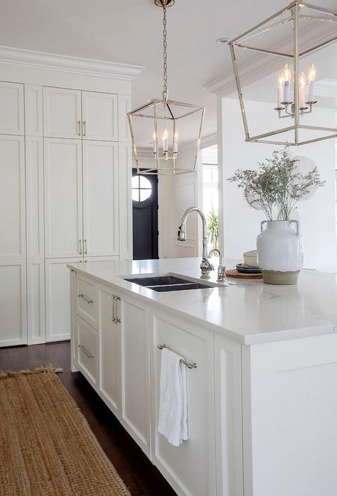 Two Darlana Lanterns hang over a white center island fitted with a stainless steel dual sink and a polished nickel gooseneck faucet. Polished Nickel Kitchen, Rainy Thursday, Bright White Kitchen, Island With Sink, Light Grey Kitchen Cabinets, Kitchen Island Tops, White Farmhouse Sink, Polished Nickel Faucet, Kitchen Island With Sink