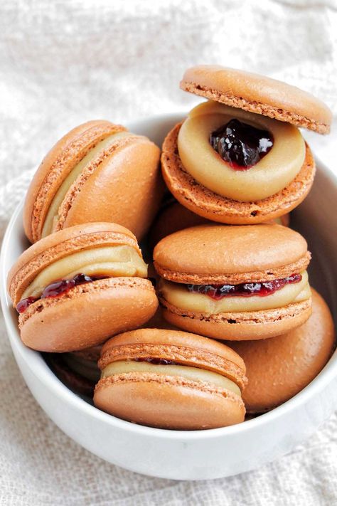 I'm obsessed with these PB&J macarons. They're filled with a peanut butter ganache macaron filling recipe, then it has a center of grape jelly. I'm going to make these again for my kids - they're perfect kid macarons - this weekend. I really love how you can change the fruit spread to make it grape, strawberry, or even raspberry flavored. It's a good sweet and salty combo. Grape Macarons, Macaron Filling Recipe, Ganache Macaron, Peanut Butter Ganache, Butter Ganache, Making Macarons, Le Macaron, Macaron Filling, Fruit Spread