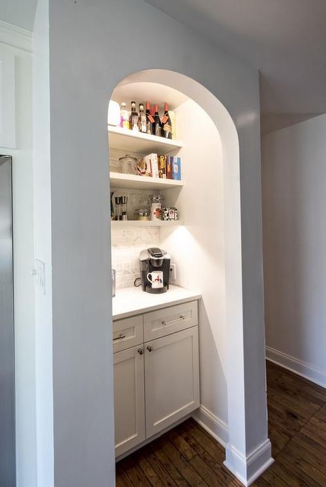 Kitchen with arched coffee station nook filled with white base cabinets topped with coffee machine under white floating shelves filled with coffee items and breakfast items lined on a linear marble tiled backsplash. Kitchen Coffee Station, Marble Tile Backsplash, Coffee Station Kitchen, Four Seasons Room, Beadboard Backsplash, White Floating Shelves, Home Coffee Stations, White Shaker Cabinets, Coffee Nook